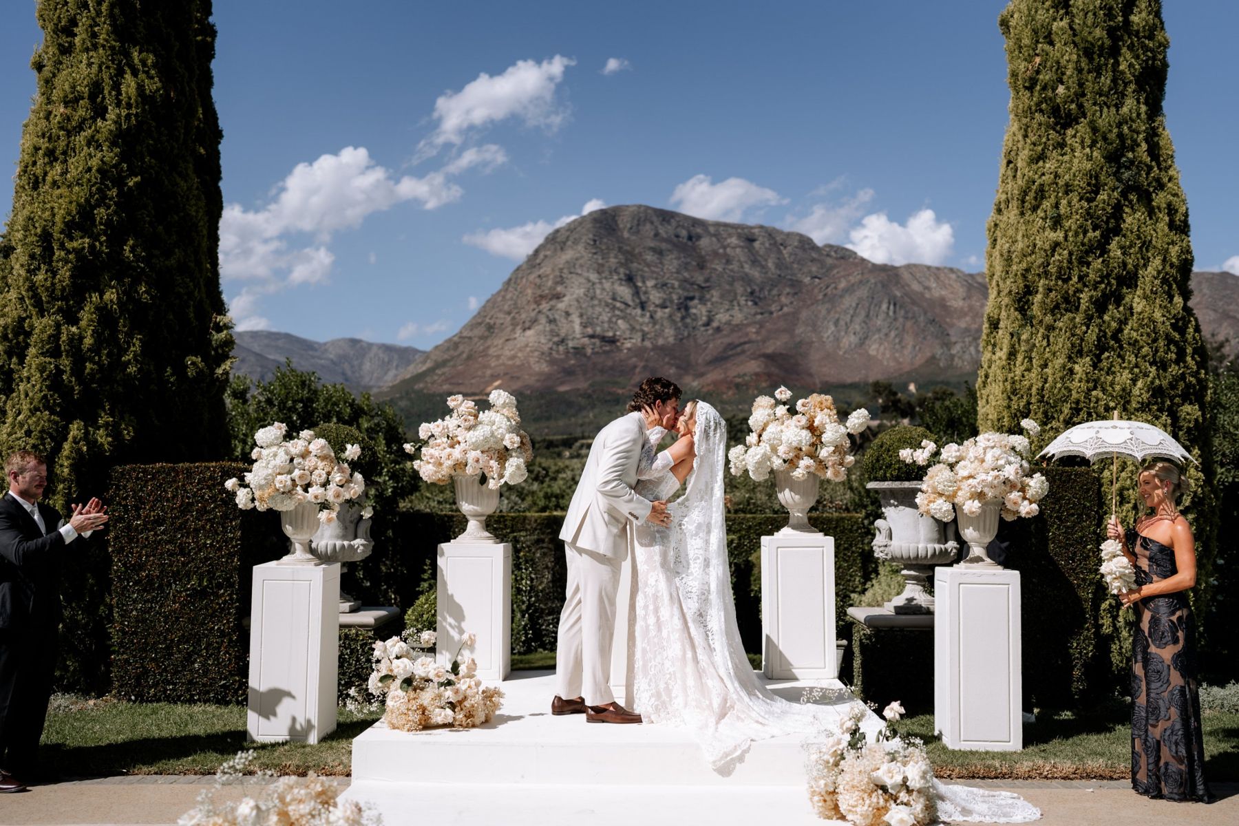 Couple's first kiss at a floral ceremony with mountains behind